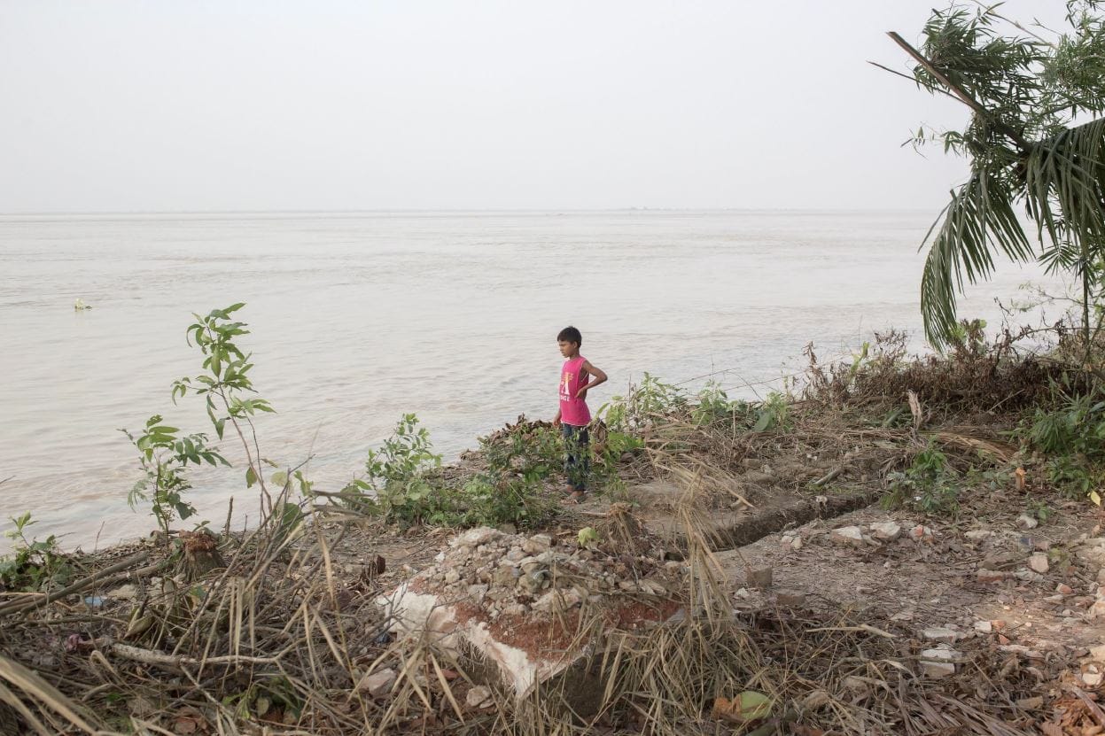 Boy visiting the ruins of a home destroyed by the Padma River.