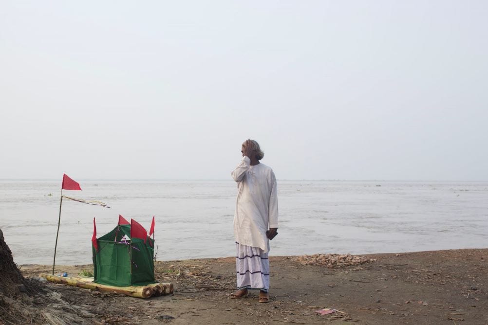Devotee crying near a shrine destroyed by the Padma River.