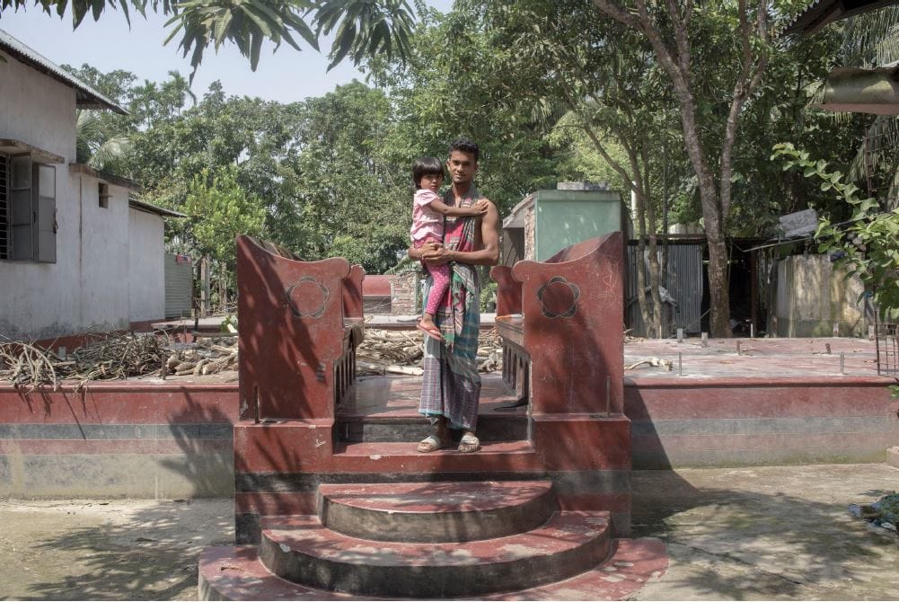 Man with his niece in front of their dismantled home near the Padma River.