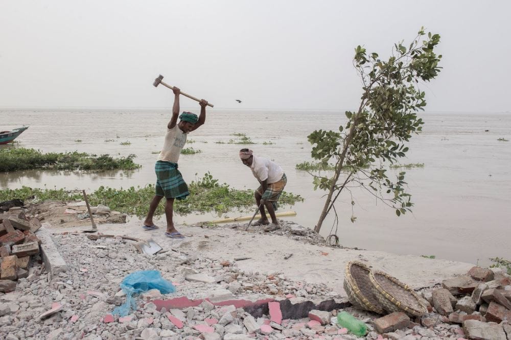 Workers salvaging remains of houses before they are lost to river erosion.