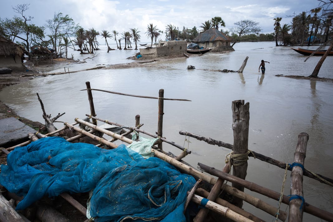 A partially submerged village in the Sundarbans delta, with flooded houses and tangled fishing nets marking the remnants of homes.