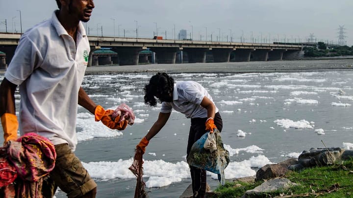 NGO workers from Namami Gange and Tree Craze Foundation clean waste along the polluted Yamuna River, joined by local residents on weekends.